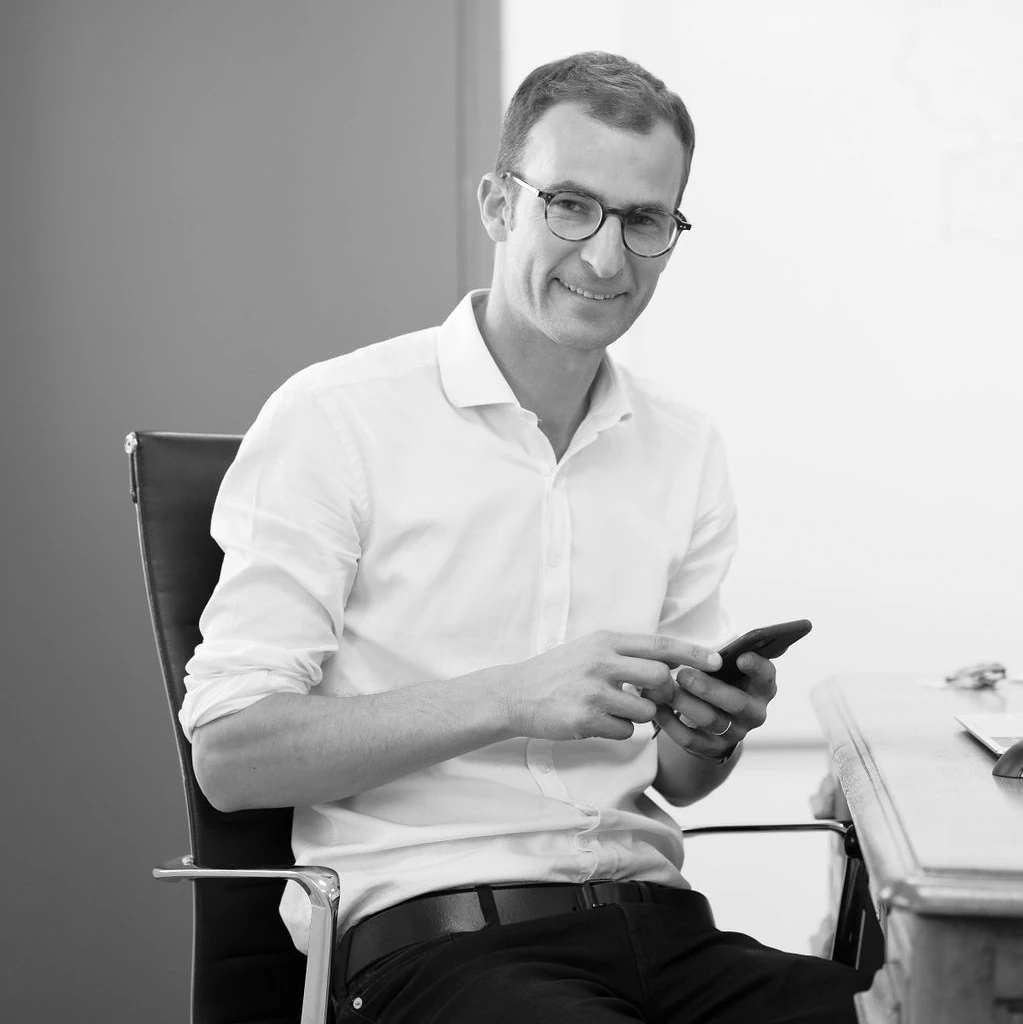 Portrait en noir et blanc du CEO de CMW, souriant, chemise blanche.